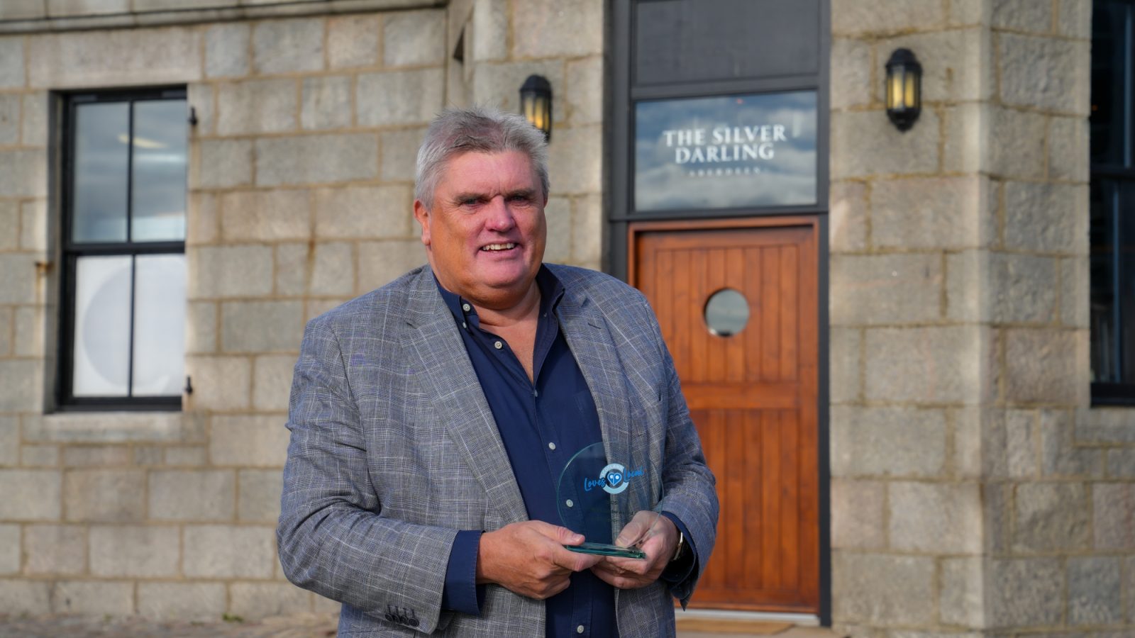 Allan Henderson with his Scotland Loves Local Place Leader Award outside The Silver Darling