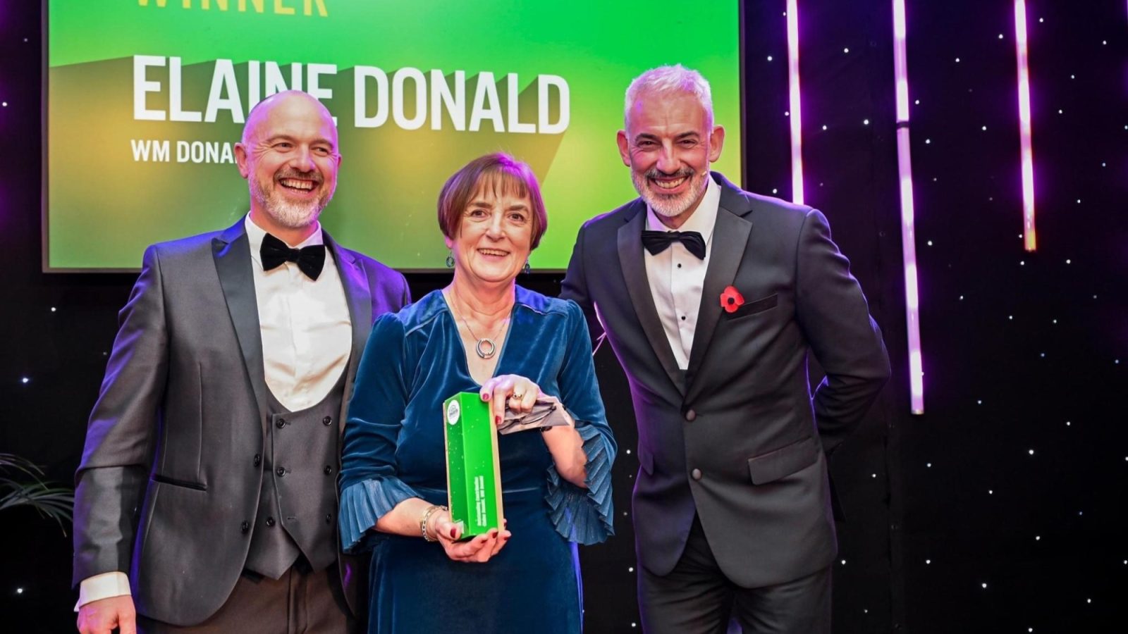 Photo from Trades Awards 2024, of Elaine Donald being presented with award for Outstanding Contribution, left to right: Andy McNair, Pre-Construction Director, CHAP Group, Elaine Donald, Director, W M Donald and host Chris Harvey, STV