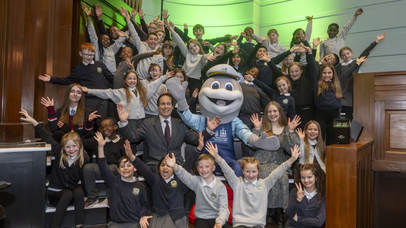 Abbotswell P4 pupils and Tall Ships mascot Dorry the Dolphin flanked by Cllr Martin Greig (left) and composer Clara-Jane Maunder (right)