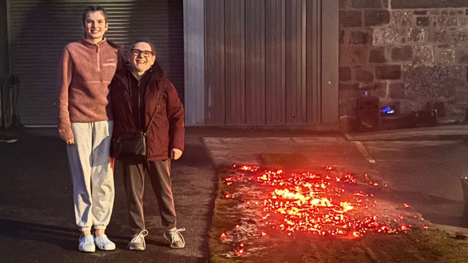 (L-R) YPSS member Talijah Reinholde and NESS added value services manager Sheila Ogden standing together smiling, to the left of the firewalk coals.