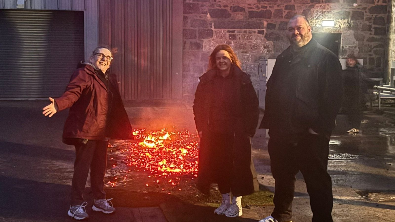 (L-R) NESS added value services manager Sheila Ogden with her hands outstretched, Sandie Sinclair and Brian Plunkett, who all took part in the firewalk, in front of the firewalk coals.
